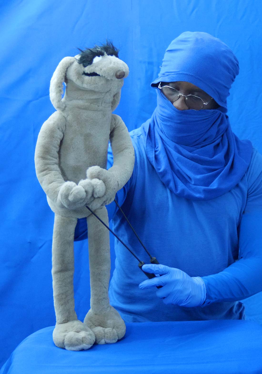 RemBunction, founder of Puppet Pavilion, carefully adjusts a handcrafted puppet in front of a blue screen backdrop in a studio setting.